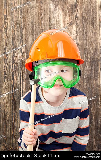 a five-year-old boy in a helmet and holds a hammer in his hand while teaching construction, a curtain plan