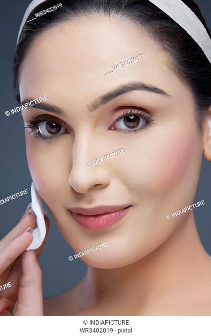Portrait of a young woman cleansing her face over white background