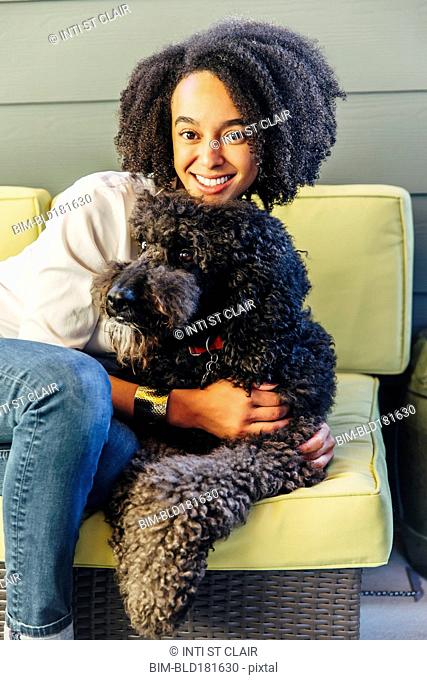 Mixed race woman hugging dog on sofa