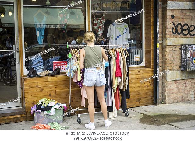 A worker adjusts the racks of a clothing in front of a store in the Williamsburg neighborhood of Brooklyn in New York on Saturday, July 22, 2017