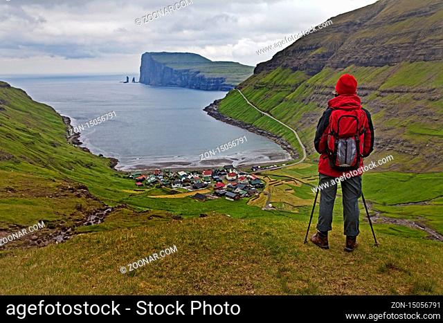 Eine Wandererin schaut auf den kleinen Ort Tjørnuvík und den Atlantik, Streymoy, Faeroeer, Føroyar, Daenemark, Europa