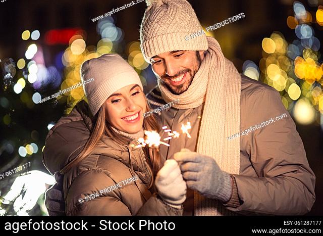 happy couple with sparklers over christmas lights