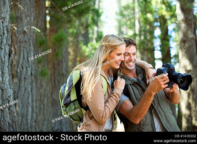 Couple looking at digital camera in woods