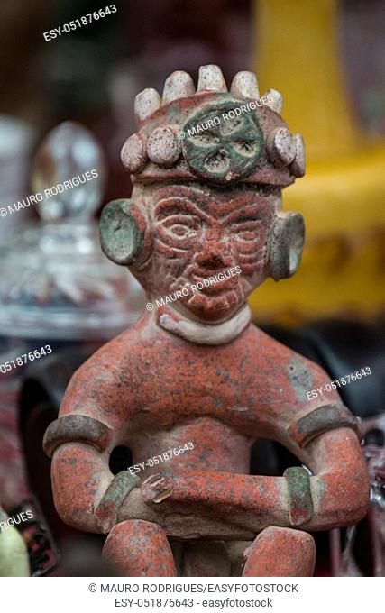 Close up view of a small red Maya statue at sale in a market