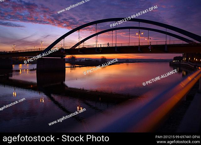 15 December 2020, Brandenburg, Frankfurt (Oder): The morning sky glows in a colourful way just before sunrise over the German-Polish border river Oder with the...