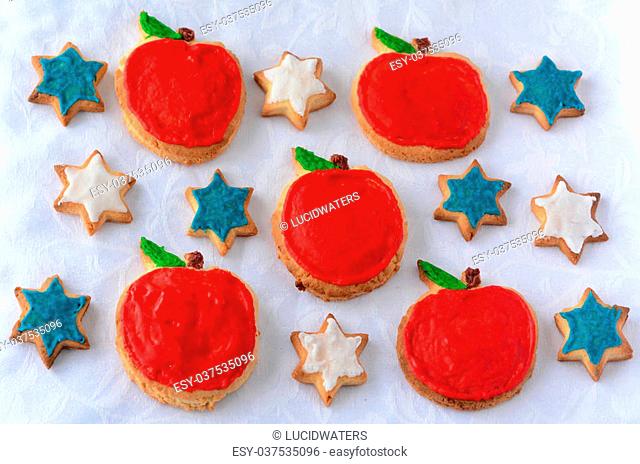 Sweet cut-out cookies in a shapes of apples and star of David decorated for Rosh Hashanah Jewish New Year holiday arrange on a table top background