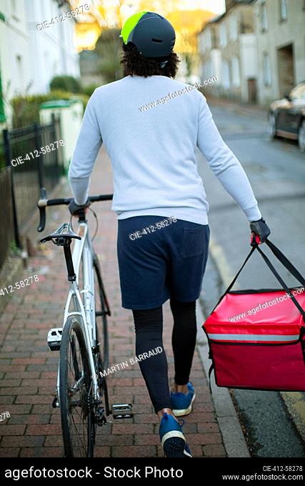 Male bike messenger delivering food in urban neighborhood