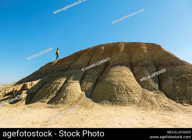 Woman walking on a hill in desertic landscape of Bardenas Reales, Arguedas, Navarra, Spain