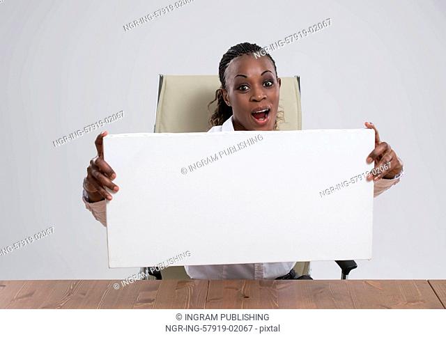 Smiling African Business woman portrait sitting at workplace with blank white board on gray isolated background Female model with long hair