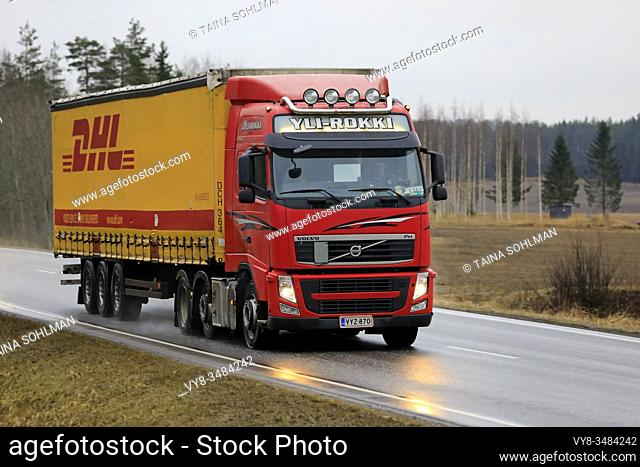 Red Volvo FH truck of Yli-Rokki hauls DHL semi trailer on highway on a rainy day. Salo, Finland. January 31, 2020.