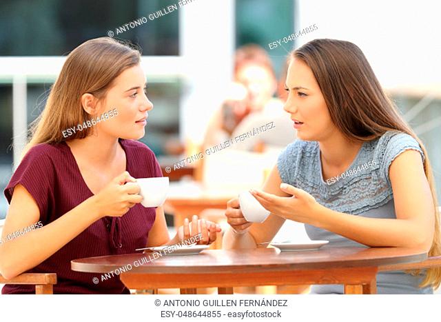 Two serious friends talking sitting in a restaurant