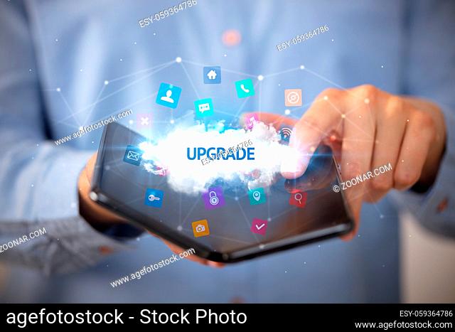 Businessman holding a foldable smartphone with UPGRADE inscription, technology concept