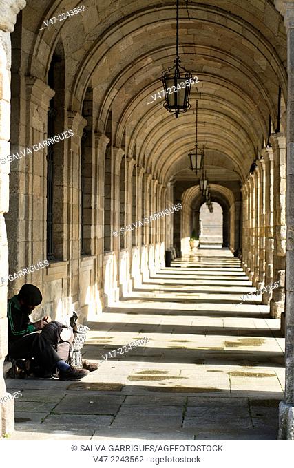 Pilgrim resting under the portico of the City of Santiago de Compostela, A Coruña. Galicia, Spain