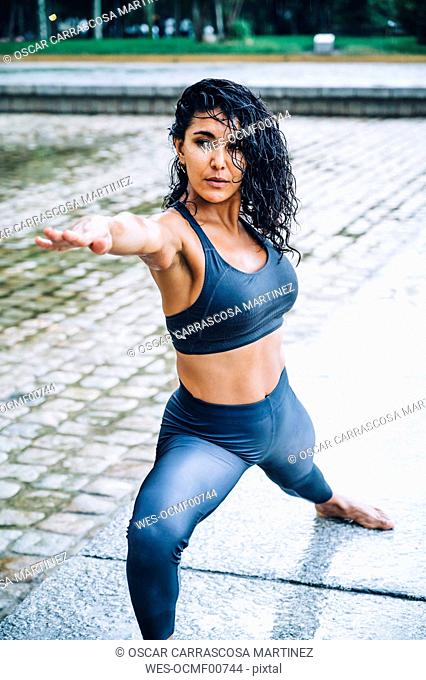 Woman practicing yoga in the rain, warrior pose