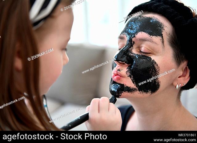 Family at home beauty treatment during coronavirus pandemic stay at home quarantine. Mother and little girl daughter make a facial mask