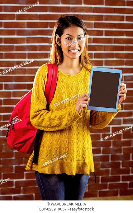 Smiling asian female student showing tablet