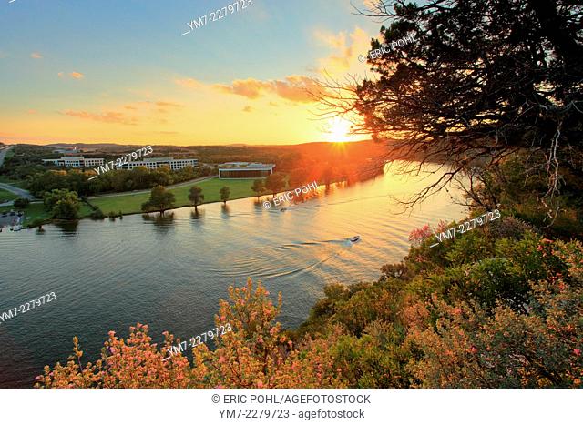 Sunset on Lake Austin - Austin, TX. As the sun sets, a boat glides down a picturesque section of the Colorado River in northwest Austin, called Lake Austin