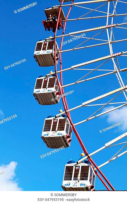 Large Ferris wheel's cabins on the blue sky