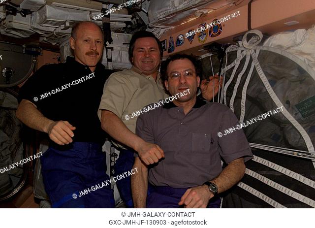 The Expedition Six crewmembers pose in the Unity node near the growing collection of insignias representing crews who have worked on the International Space...