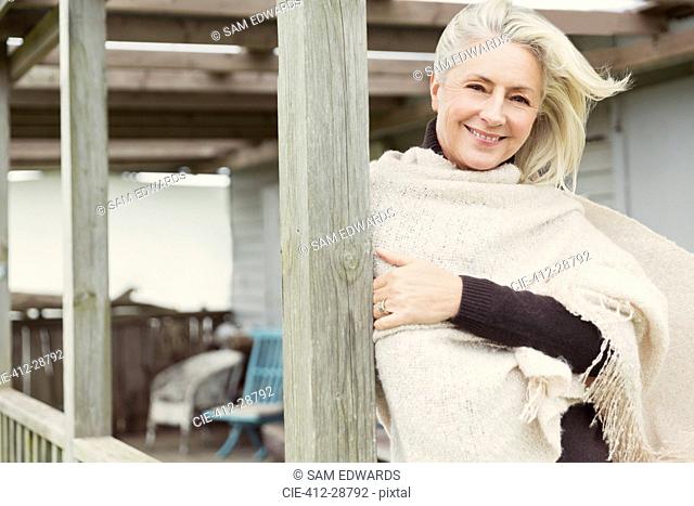 Portrait smiling senior woman wearing shawl on windy porch