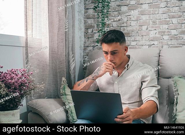One serious and focused young entrepreneur working hard and analyzing market at home. Teenager boy studying and doing homework for school alone