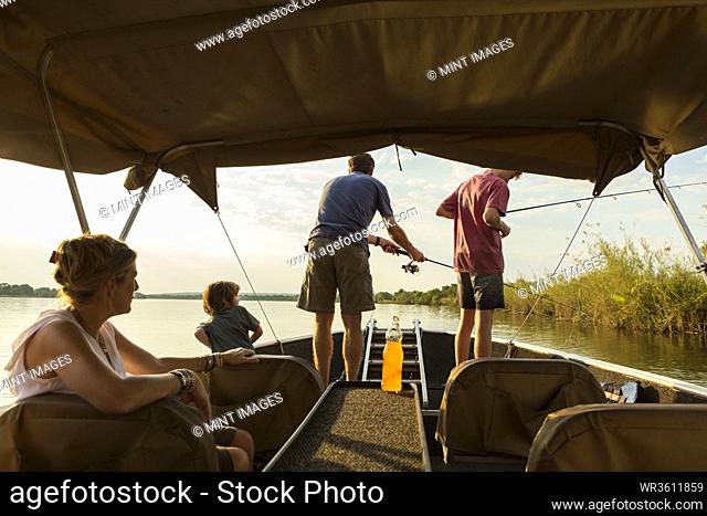 A group of tourists, family fishing from a boat on the Zambezi River, Botswana