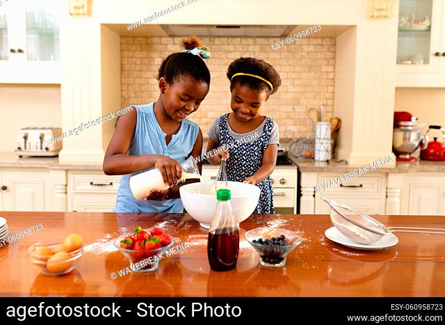 Two african american sisters baking together in the kitchen at home