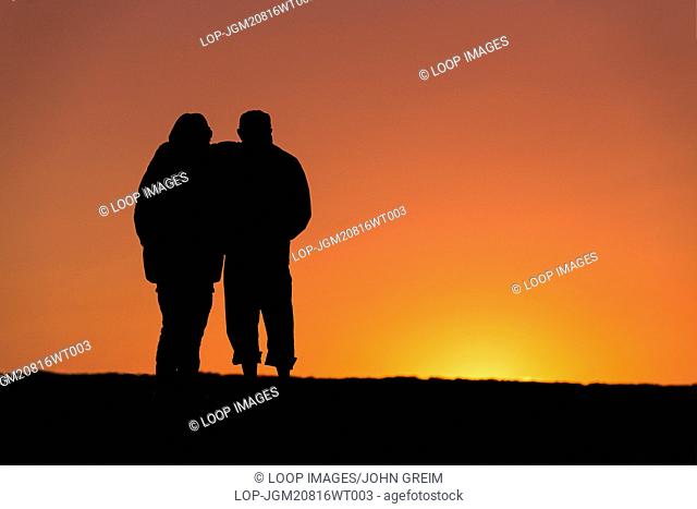 Senior couple enjoys sunset from a jetty