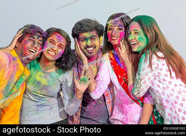 A HAPPY GROUP OF YOUNG MEN AND WOMEN POSING TOGETHER DURING HOLI CELEBRATIONS