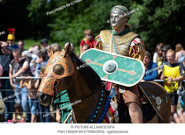 09 June 2019, Lower Saxony, Bramsche: A Roman actor with mask and shield rides on a horse with blinders at the Römer- und Germanentage in the Museum und Park...