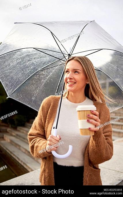 Smiling woman with bamboo cup against retaining wall during rainy season