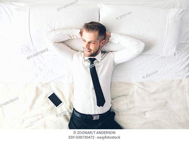 Top view. Young handsome businessman relaxing on bed after a tough day at work