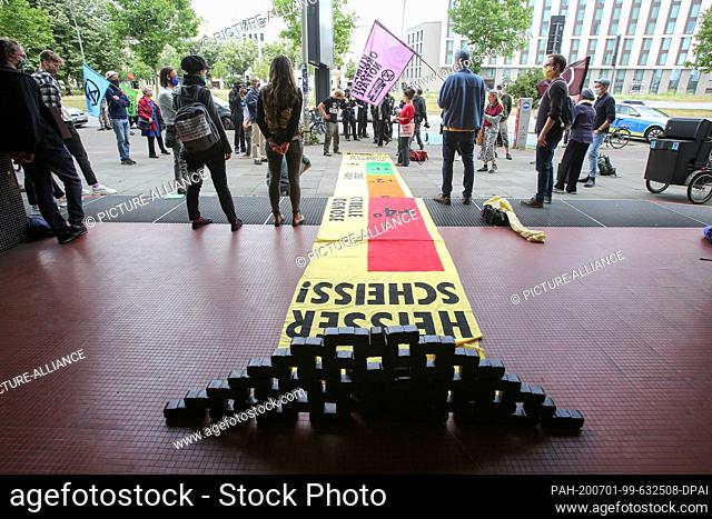 01 July 2020, Hamburg: With briquettes and banners, among other things with the inscription ""Heisser Scheiss!"" (hot shit) activists protest in front of the...