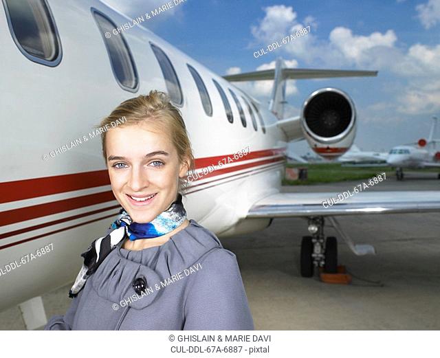 Smiling flight attendant beside private jet
