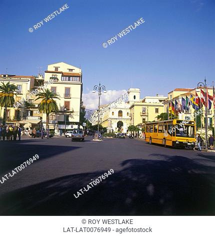 Piazza Tasso. large square with bus/ cars. Shops. Yellow buildings. Flags. Palm trees