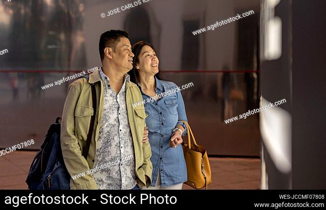 Smiling mature couple by illuminated information sign