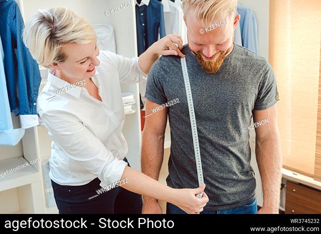 Tailor measuring customer with measuring tape in her studio