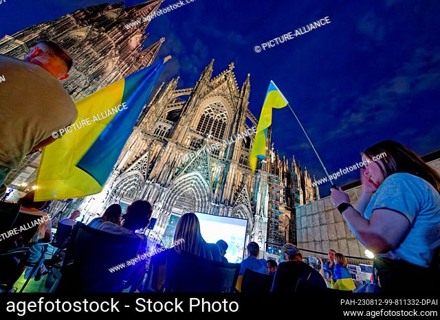 11 August 2023, North Rhine-Westphalia, Cologne: Participants stand in front of the cathedral at the event ""Unbreakable Ukraine - Night Rally for the Future of...
