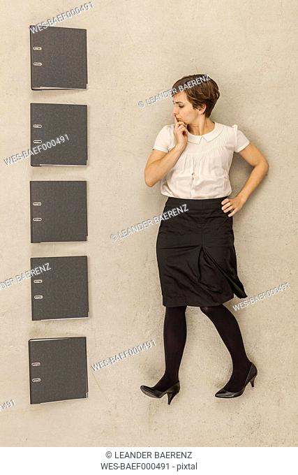 Businesswoman standing besides stack of files