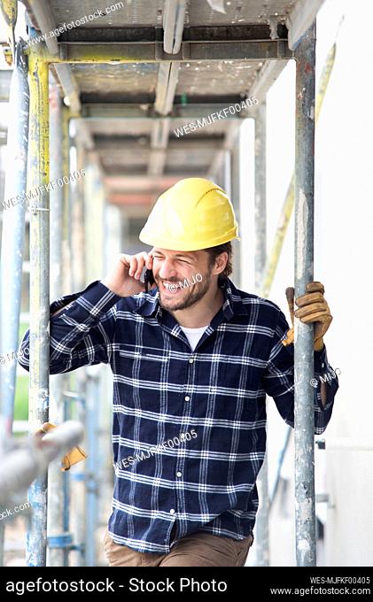 Construction worker talking over smart phone while standing by scaffold