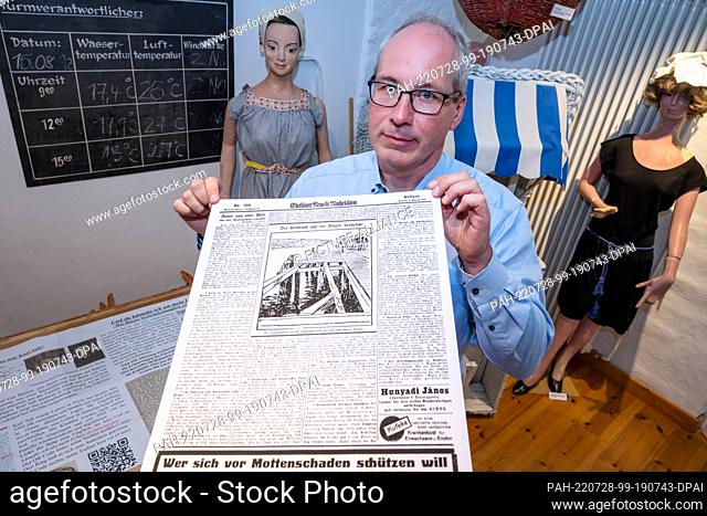 28 July 2022, Mecklenburg-Western Pomerania, Binz: Arndt Schmitz, shows a newspaper page from 1912 at the Binz Museum. Schmitz's grandfather was a survivor of...