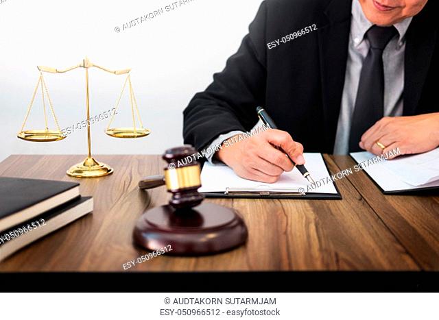 lawyer hand writes the document in court (justice, law) with sounding block and golden Weight