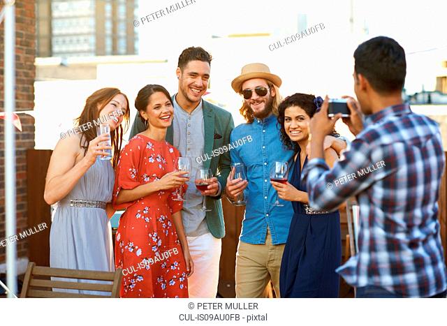 Friends taking photograph at early evening party