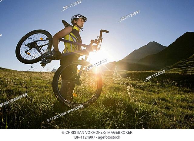 Mountain biker carrying his bike, Zillertal Alps, Mayerhofen, North Tyrol, Austria, Europe