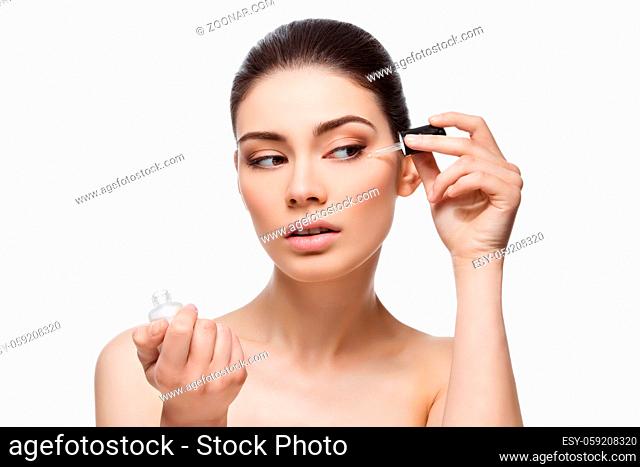 Beautiful young woman applying anti-ageing moisturizing serum to under eye area. Isolated over white background. Copy space