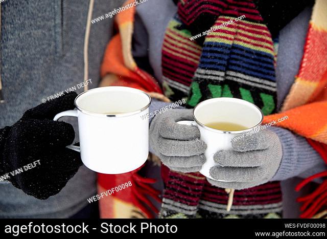 Couple holding mugs with tea during winter