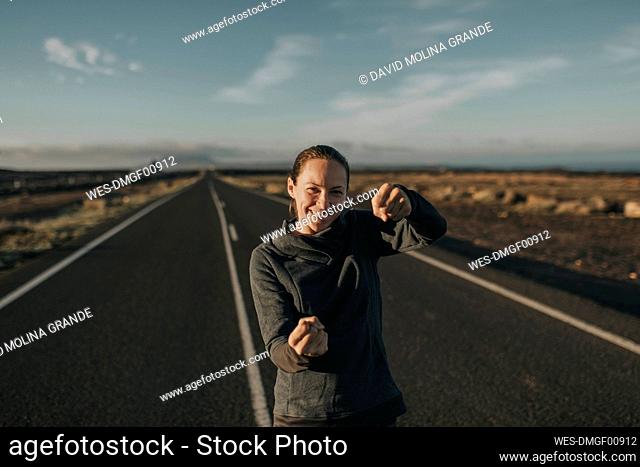 Smiling woman holding invisible steering wheel on empty road