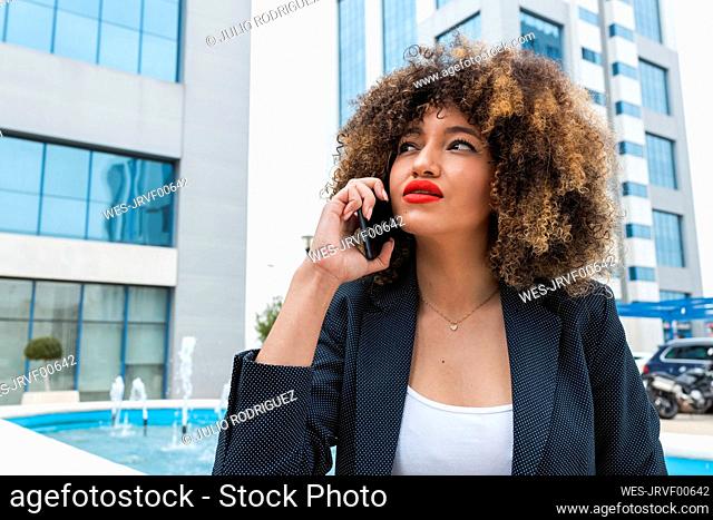 Beautiful Afro female professional talking on mobile phone in city