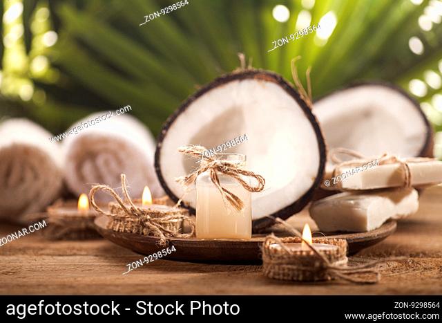 Coconuts and coconut oil on wooden table, on nature background. Health spa background