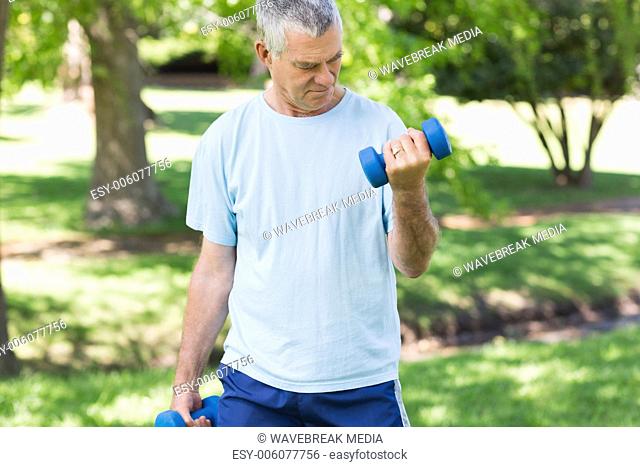 Mature man with dumbbells at park